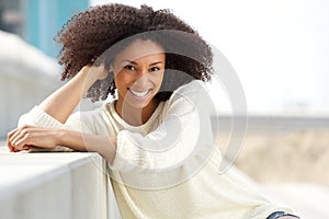 Smiling african american woman with curly hair sitting outdoors