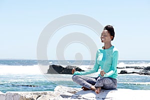 Smiling african american woman doing yoga by the sea