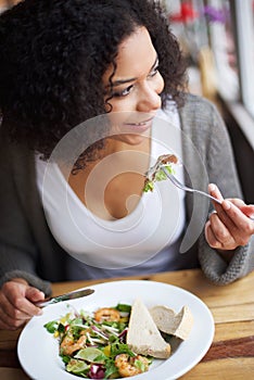 Smiling african american woman eating in restaurant