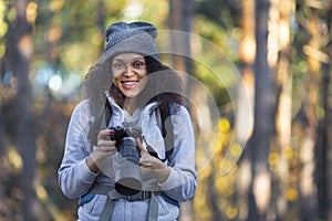 Smiling African American woman in the forest with a camera.