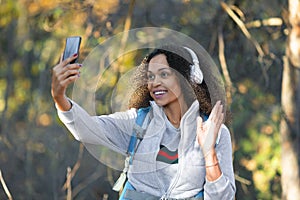 Smiling African American woman in the forest taking a selfie on a smartphone.