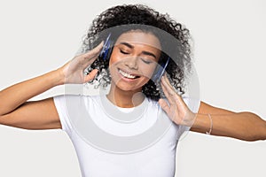 Smiling African American woman in headphones enjoying favorite music