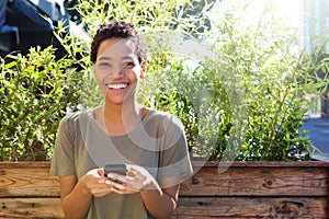 Smiling african american woman holding mobile phone outdoors