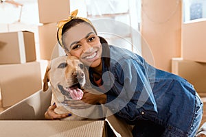 smiling african american woman with labrador dog in cardboard