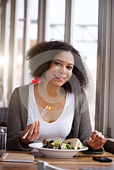 Smiling african american woman in restaurant eating salad