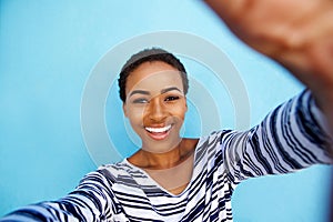 Smiling african american woman taking selfie against blue wall photo