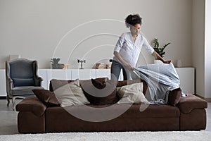 Smiling African American woman tenant cleaning or decorating modern apartment