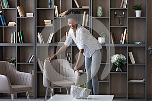 Smiling African American woman tenant renter decorating modern apartment