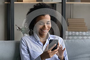 Smiling African American woman use smartphone at home