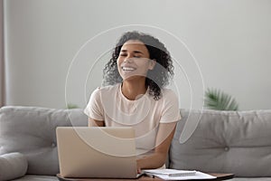 Smiling African American woman using laptop, chatting online, having fun