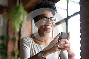 Smiling African American woman using phone, get good message