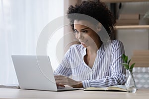 Smiling African American woman working on laptop online, typing