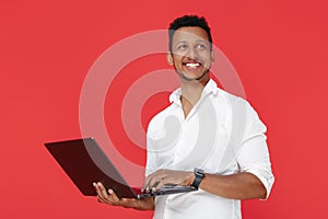 Smiling african american young man holding notebook over red background.