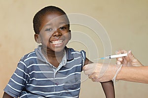 Smiling African boy sitting whilst getting an injection from an European Volunteer
