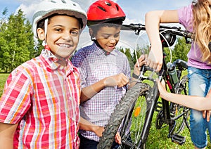 Smiling African boys in helmets repair bike