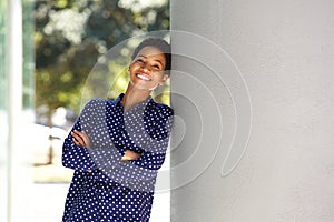 Smiling african business woman leaning against wall