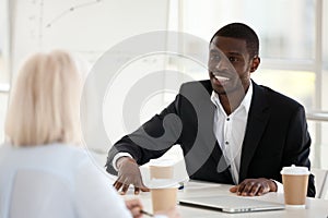 Smiling african businessman in suit speaking to colleague at mee