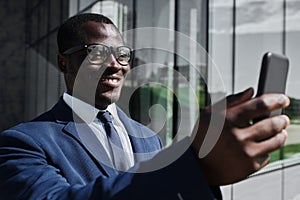 Smiling african businessman using smart phone outdoor