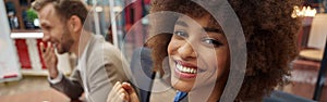 Smiling african businesswoman sitting on his workplace in modern office on colleague background