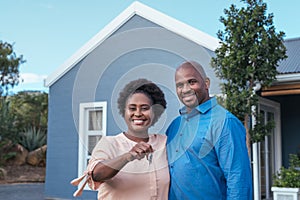 Smiling African couple standing with keys to their new home