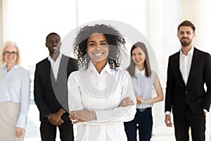 Smiling african employee standing with diverse team in office, p