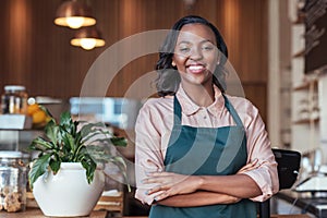 Smiling African entrepreneur standing at the counter of her cafe