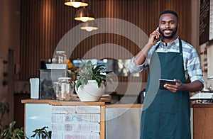 Smiling African entrepreneur talking on a cellphone in his cafe