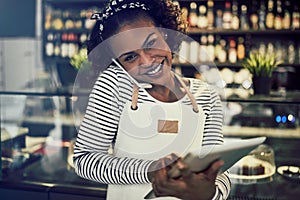 Smiling African entrepreneur talking on the phone in her cafe