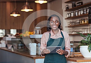 Smiling African entrepreneur using a digital tablet in her cafe