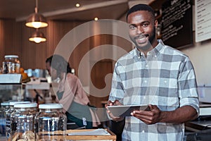 Smiling African entrepreneur working at the counter of his cafe