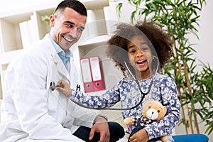 Smiling african girl playing with pediatrician