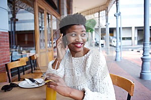 Smiling african girl using mobile phone at outdoor cafe