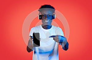 Smiling african guy with wireless headphones showing smartphone