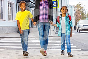 Smiling African kids with woman walk on the street