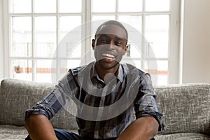 Smiling african male vlogger looking at camera sitting on couch photo