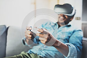 Smiling african man enjoying virtual reality glasses while sitting on sofa.Young guy with vr headset or 3d spectacles