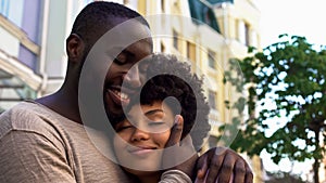 Smiling african man hugging girlfriend, loving couple, outdoor romantic date