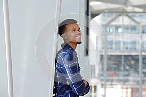 Smiling african man leaning against wall with arms crossed