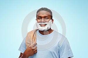 Smiling african man with shaving cream and towel