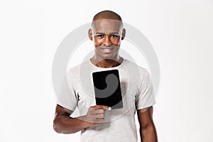 Smiling african man showing blank tablet computer screen