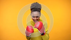Smiling african teenager in boxing gloves imitating fight, having fun, victory