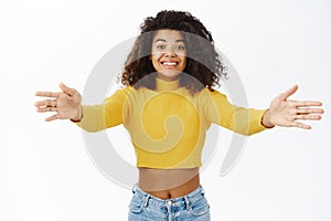Smiling african woman reaching hands and hugging, cuddle, receive something, stretching arms, standing in stylish outfit