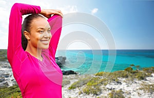 Smiling african woman stretching hand on beach