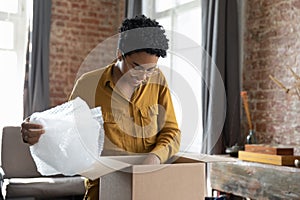 Smiling African woman unpack received parcel box