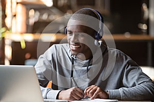 Smiling african young man student wearing headphones study online