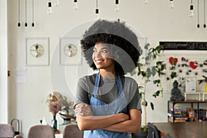 Smiling African young woman cafe small business owner standing arms crossed.