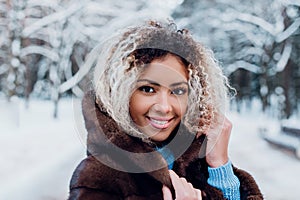 Smiling afro american girl wearing in fur coat in winter park