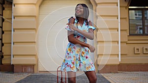 Smiling afro girl dancing bachata in city. African woman moving body on street