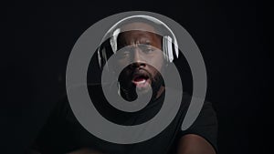 Smiling afro guy dancing indoors. Portrait of funny african man in headphones