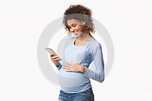 Smiling afro pregnant woman using mobile phone